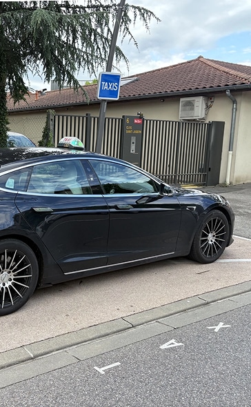 Taxi Tesla stationné : borne Quai Saint-Joseph Berline Tesla noire stationnée à une borne de taxis française, panneau TAXIS bleu visible et inscription "6 Quai Saint-Joseph" sur le portail.